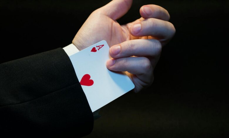 A magician's hand showing an ace of hearts hidden up the sleeve, symbolizing magic and trickery.