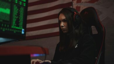 A female gamer intensely focused on her screen, wearing a headset in a dark room with neon green lighting.