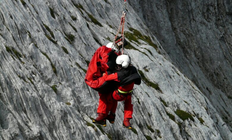 Two rescuers in action on a mountain, showcasing teamwork and safety in a daring lift.