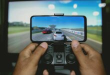 Close-up of hands playing a racing game on a mobile device with a controller.
