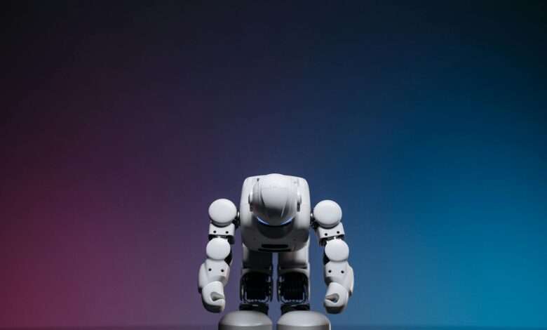 White robot in a bowing pose against a gradient studio background.