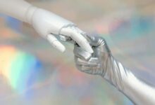 Close-up of a robot hand and silver-gloved hand touching, symbolizing human-robot connection.