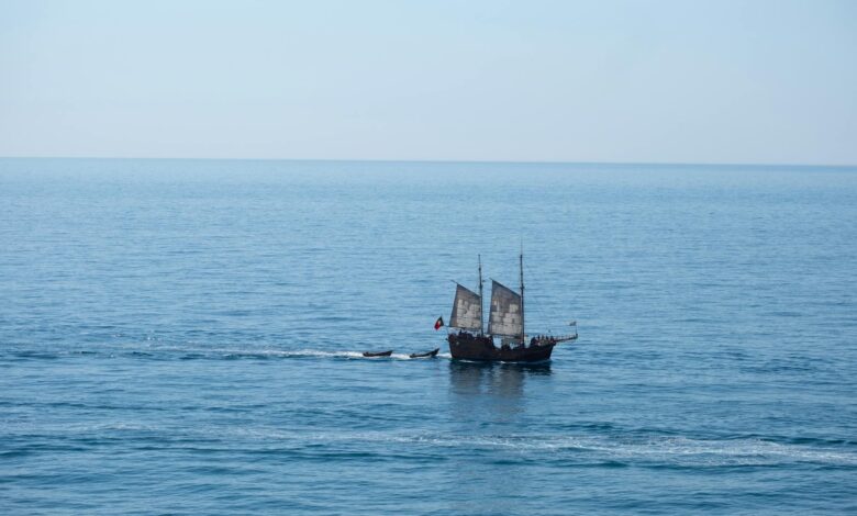 A majestic pirate ship sails across the calm waters of the Algarve coast.