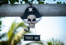 Decorative pirate skull sign with 'Pirates Only' text hanging outdoors on a sunny day.