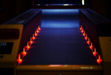 A vibrant neon-lit bowling lane creating a dynamic and dark atmosphere indoors.