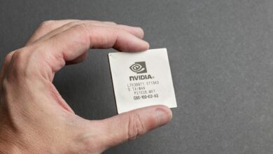A close-up view of a person holding an Nvidia chip with a gray background.