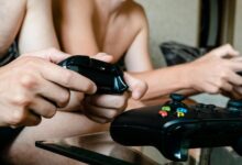 Close-up of adults playing video games with joysticks. Intense multiplayer gaming session.