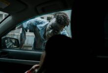 Frightening zombie peering through a car window during a horror scene.