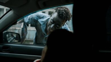 Frightening zombie peering through a car window during a horror scene.