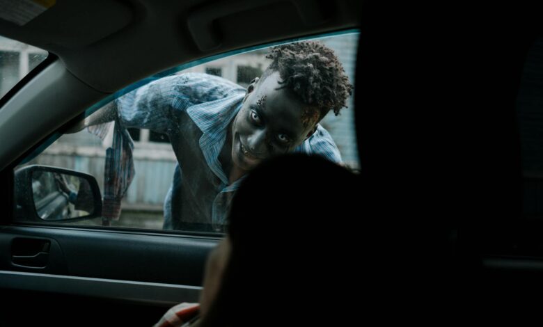 Frightening zombie peering through a car window during a horror scene.