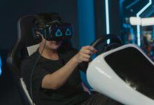 Man engaging in immersive virtual gaming with VR headset and steering wheel setup indoors.