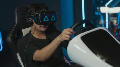Man engaging in immersive virtual gaming with VR headset and steering wheel setup indoors.