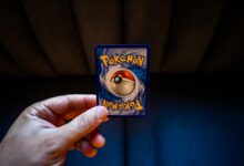 Crop unrecognizable person demonstrating collectible card dedicated to fictional creatures on dark background