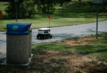 Autonomous delivery robot on a park pathway, showcasing modern technology in a natural outdoor setting.