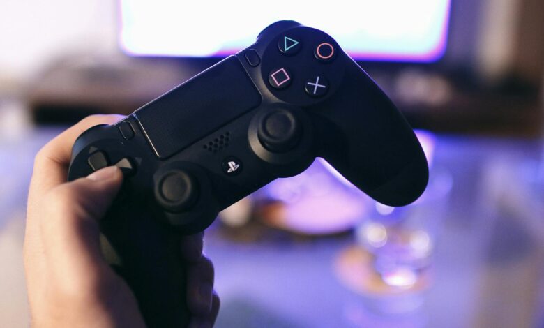 Person holding a gaming controller, blurred screen in background.