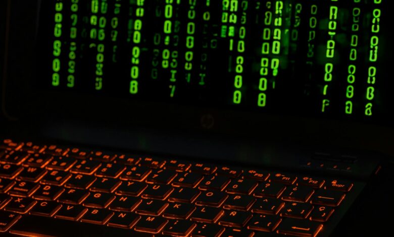 A laptop keyboard with orange backlight displaying green digital code symbols.