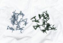 Colorful army toy figures arranged on a white cloth in aerial view.