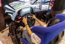 Person using a realistic VR racing simulator at a gaming event, focused on the immersive experience.