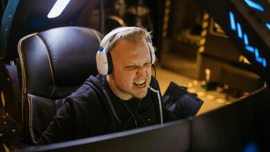 A passionate gamer celebrating victory while gaming indoors with white headphones and a gaming chair.