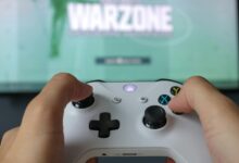A close-up of hands holding an Xbox controller against a game screen, highlighting the gaming experience.