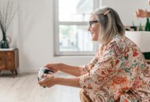 Elderly woman enjoying a video game session indoors, showcasing active lifestyle.