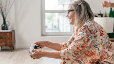 Elderly woman enjoying a video game session indoors, showcasing active lifestyle.