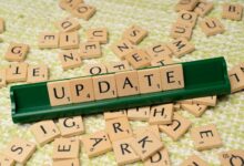 Wooden Scrabble tiles spelling 'UPDATE' with scattered tiles on a textured surface.