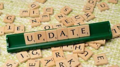 Wooden Scrabble tiles spelling 'UPDATE' with scattered tiles on a textured surface.