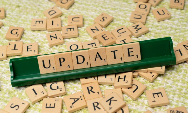 Wooden Scrabble tiles spelling 'UPDATE' with scattered tiles on a textured surface.
