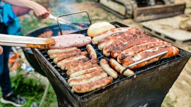 Grilling an assortment of sausages and bread at an outdoor barbecue on a sunny day.