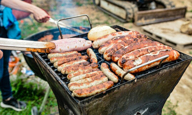 Grilling an assortment of sausages and bread at an outdoor barbecue on a sunny day.