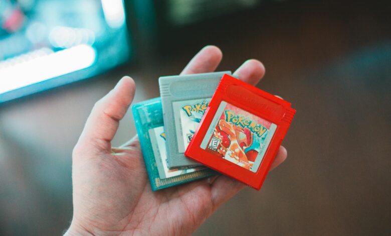 Hand holding vintage Pokemon game cartridges, showcasing nostalgic gaming.