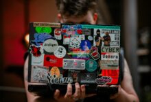 A person holds a laptop with vibrant stickers, showcasing creativity and personal expression.