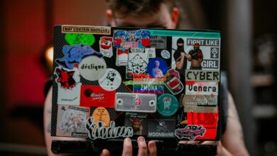 A person holds a laptop with vibrant stickers, showcasing creativity and personal expression.