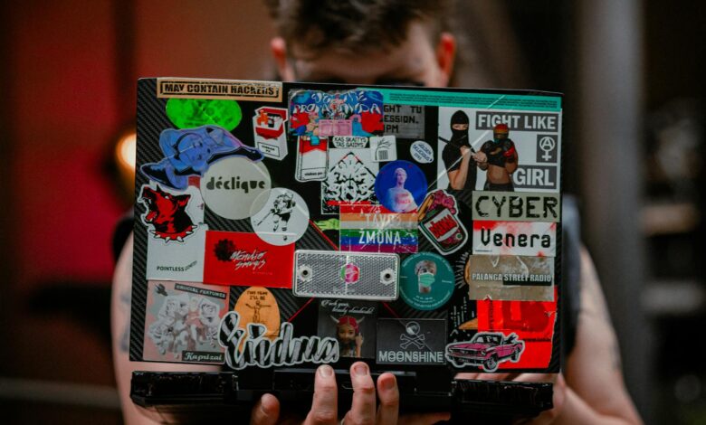 A person holds a laptop with vibrant stickers, showcasing creativity and personal expression.