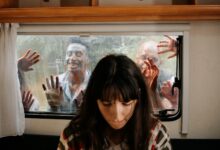 A woman sits unaware while terrifying zombies threaten through the window.
