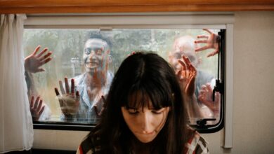 A woman sits unaware while terrifying zombies threaten through the window.