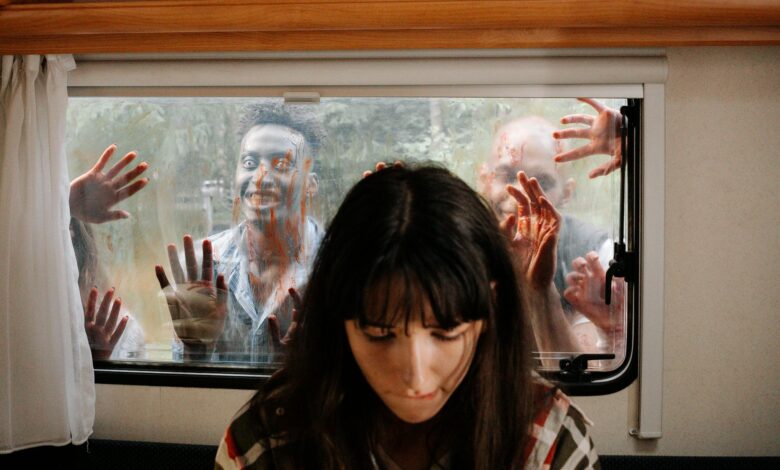 A woman sits unaware while terrifying zombies threaten through the window.