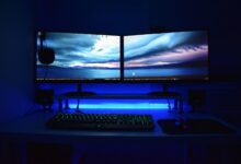 Dual monitors with blue lighting on a gaming desk setup.