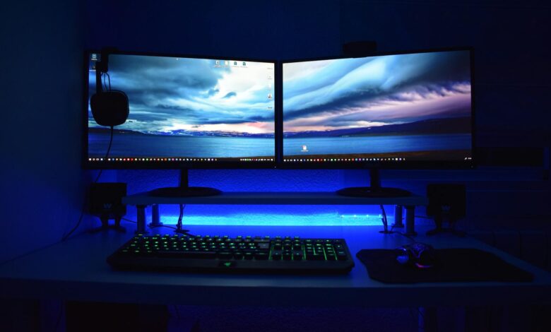 Dual monitors with blue lighting on a gaming desk setup.