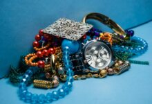 A close-up shot of various colorful jewelry pieces with a stylish wristwatch on blue background.