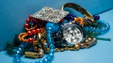 A close-up shot of various colorful jewelry pieces with a stylish wristwatch on blue background.