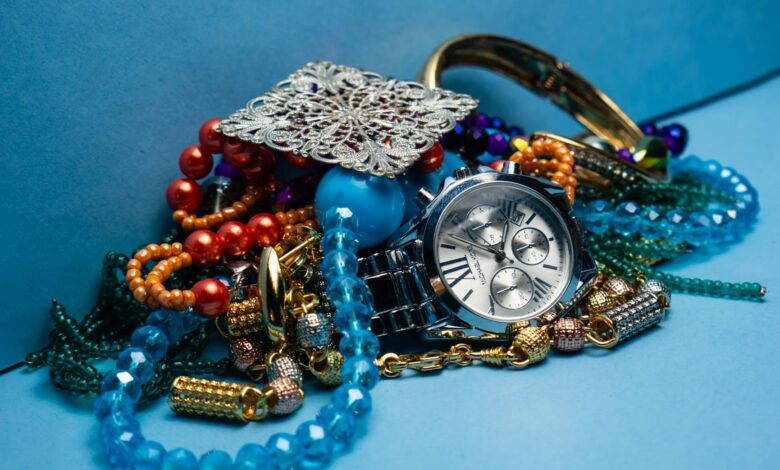 A close-up shot of various colorful jewelry pieces with a stylish wristwatch on blue background.