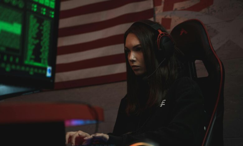 A female gamer intensely focused on her screen, wearing a headset in a dark room with neon green lighting.