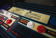 Close-up of a vintage arcade game control panel with colorful buttons and instructions.