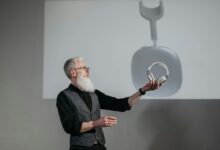 Mature man presenting wireless headphones in a business setting.