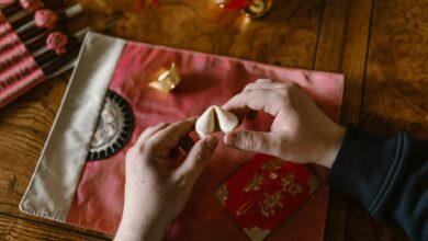 Hands holding a fortune cookie above a red envelope, symbolizing luck and tradition.