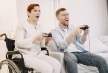 A joyful scene of an adult man and senior woman playing video games indoors, embracing technology and fun.