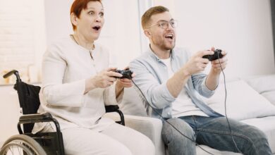A joyful scene of an adult man and senior woman playing video games indoors, embracing technology and fun.