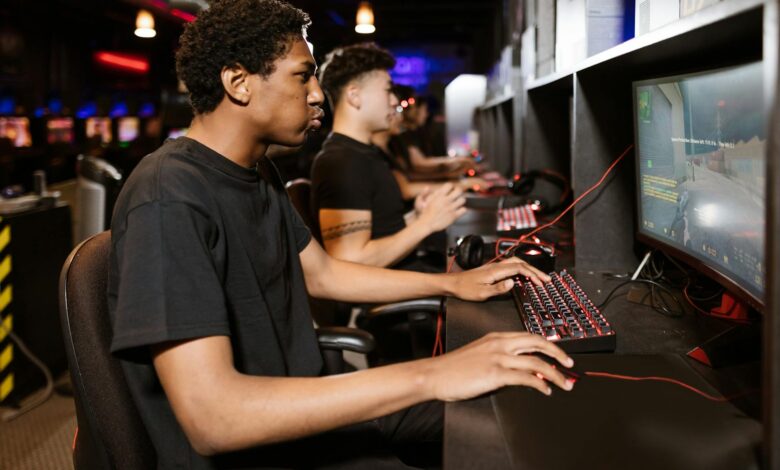 Group of young adults deeply engaged in competitive online gaming at a cyber cafe.